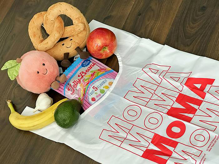 「MoMA Mart」のショッピングバッグから飛び出しているぬいぐるみやポーチ